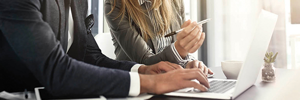 Homme et femme d'affaires assis à un bureau et travaillant côte à côte en regardant un ordinateur portable.